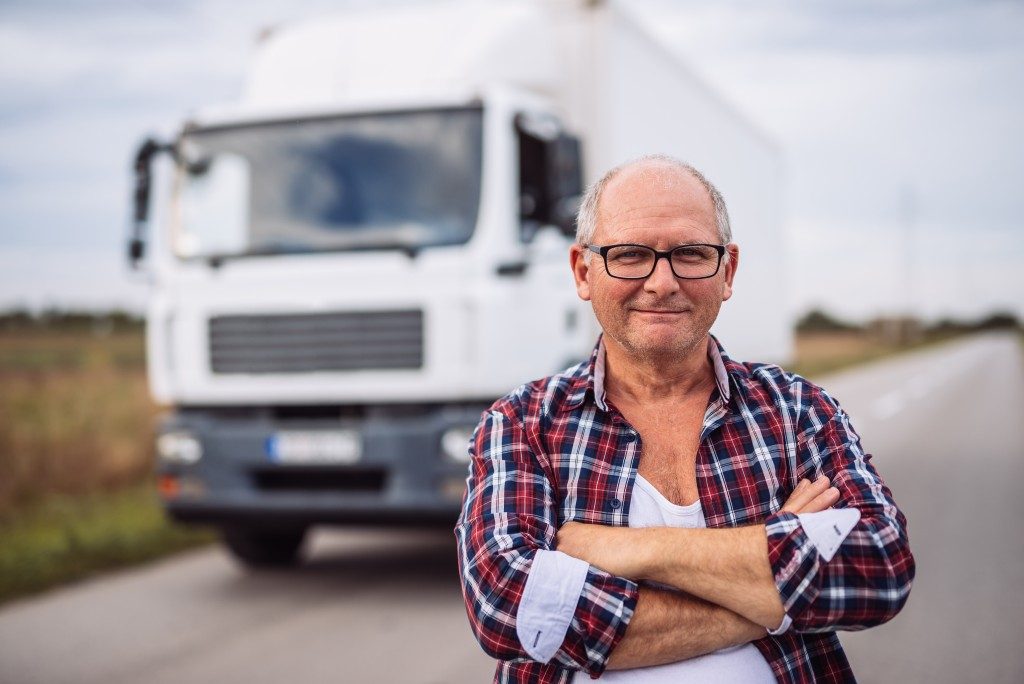 Middle aged driver posing with a truck on the background