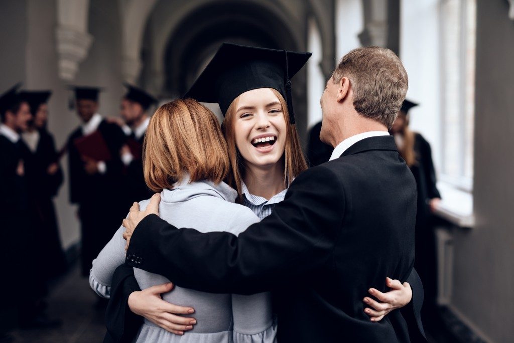 Student hugging her parents after graduating