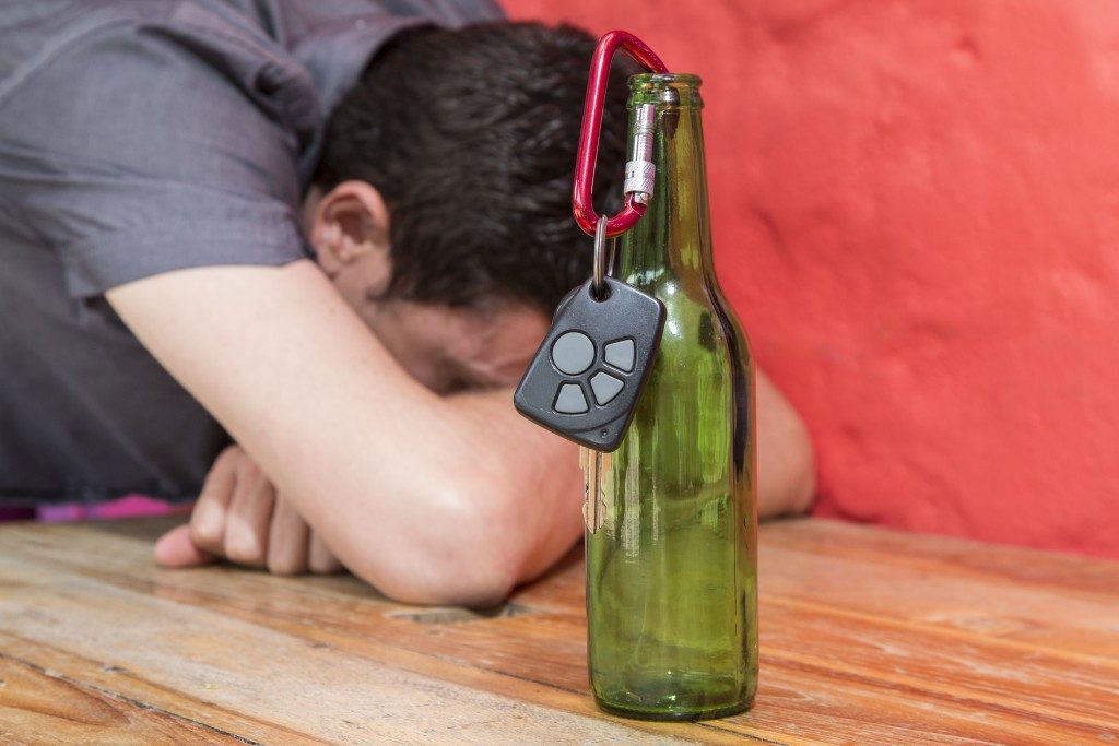 car key hanging from a bottle of beer in the background drunk man