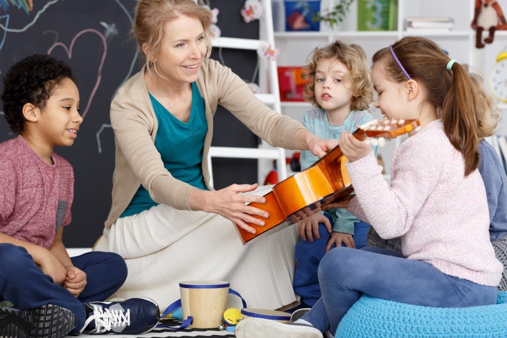 Instructor teaching students how to play the guitar