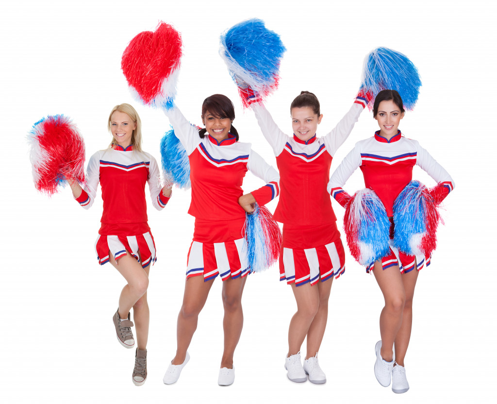 Group of young cheerleaders in red uniform. Isolated on white background