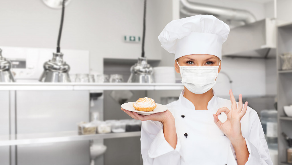 female chef in toque wearing face protective medical mask for protection